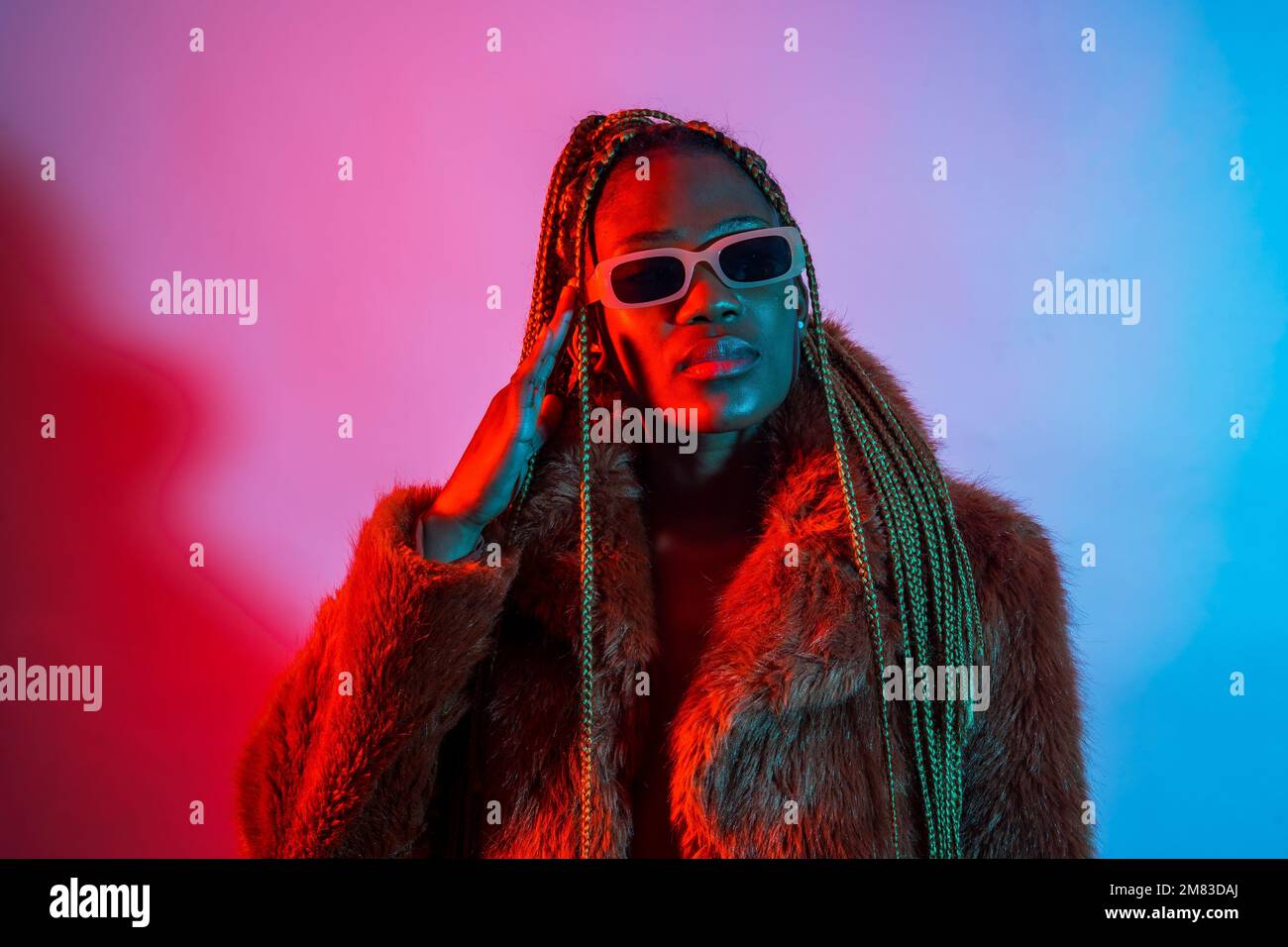 A studio portrait of an African young woman with braids posing under ...