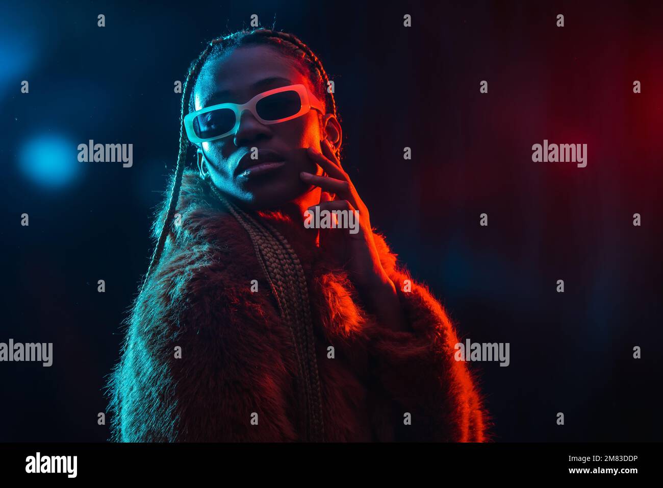 A portrait of an African young woman with braids wearing a coat posing ...