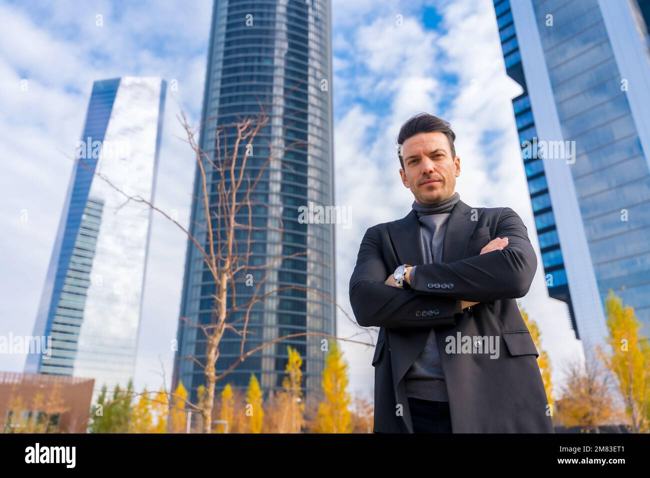 A Caucasian businessman with crossed arms standing in front of building ...