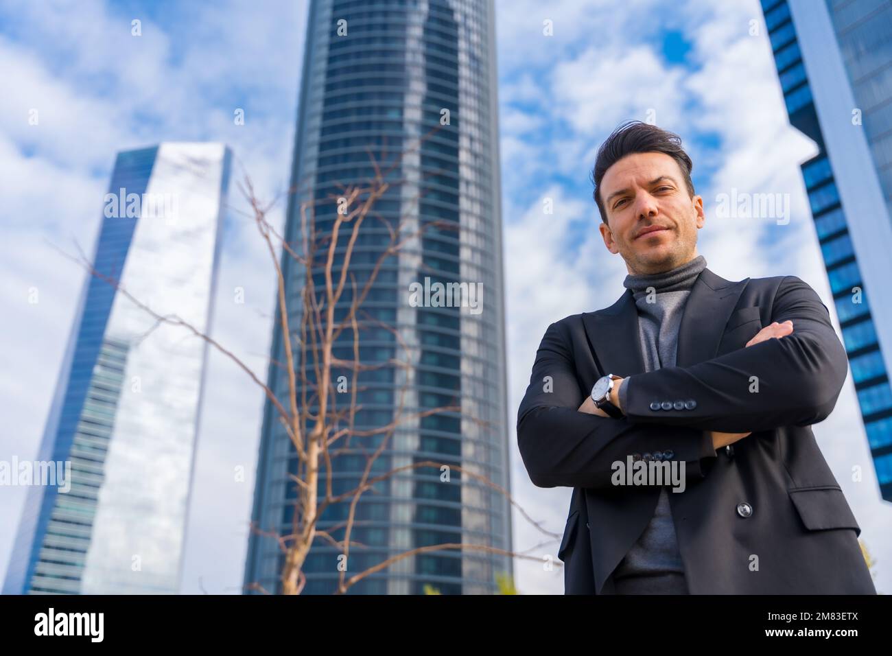 A Caucasian businessman with crossed arms standing in front of building ...