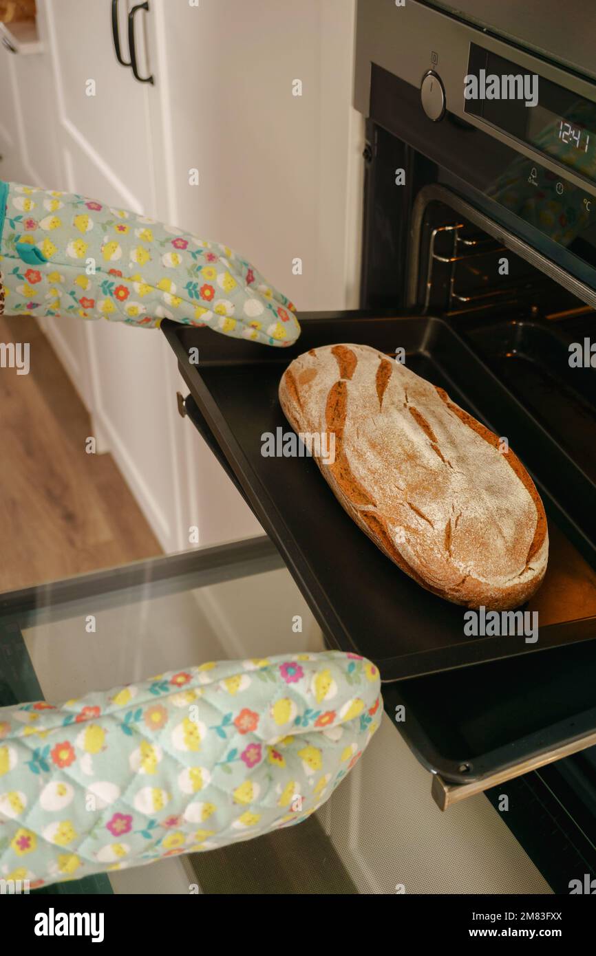 loaf of bread in the oven tray with oven mitts Stock Photo