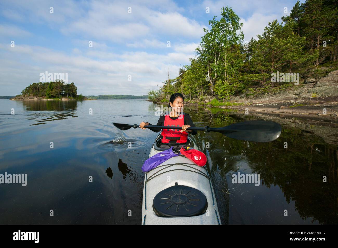 A woman is paddling a kayak in the lake Vansjø in Østfold, Norway, Scandinavia. Stock Photo