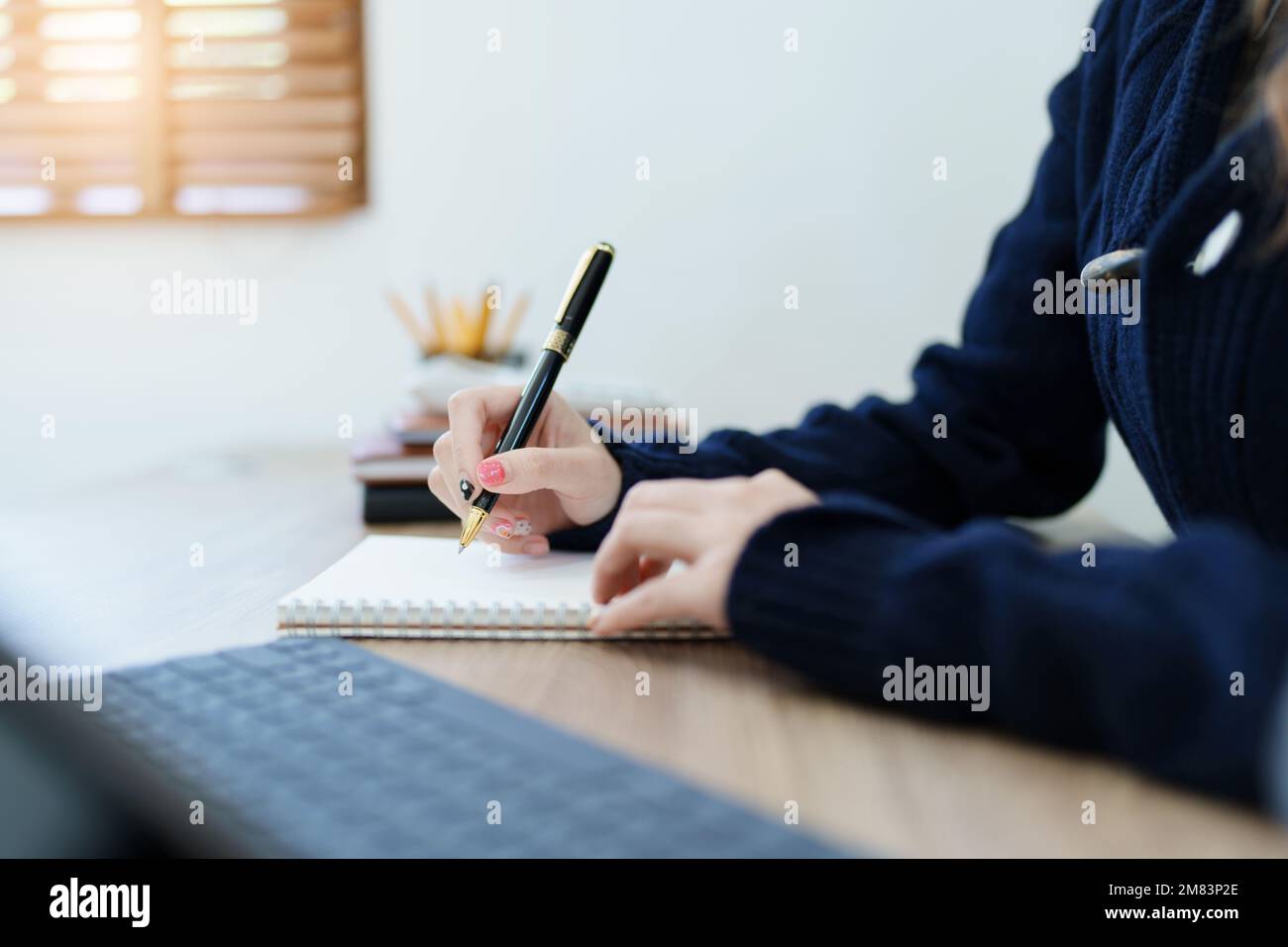 Portrait of a young Asian man showing a smiling face as she uses his notebook, tablet computer and financial documents on her desk in the early Stock Photo
