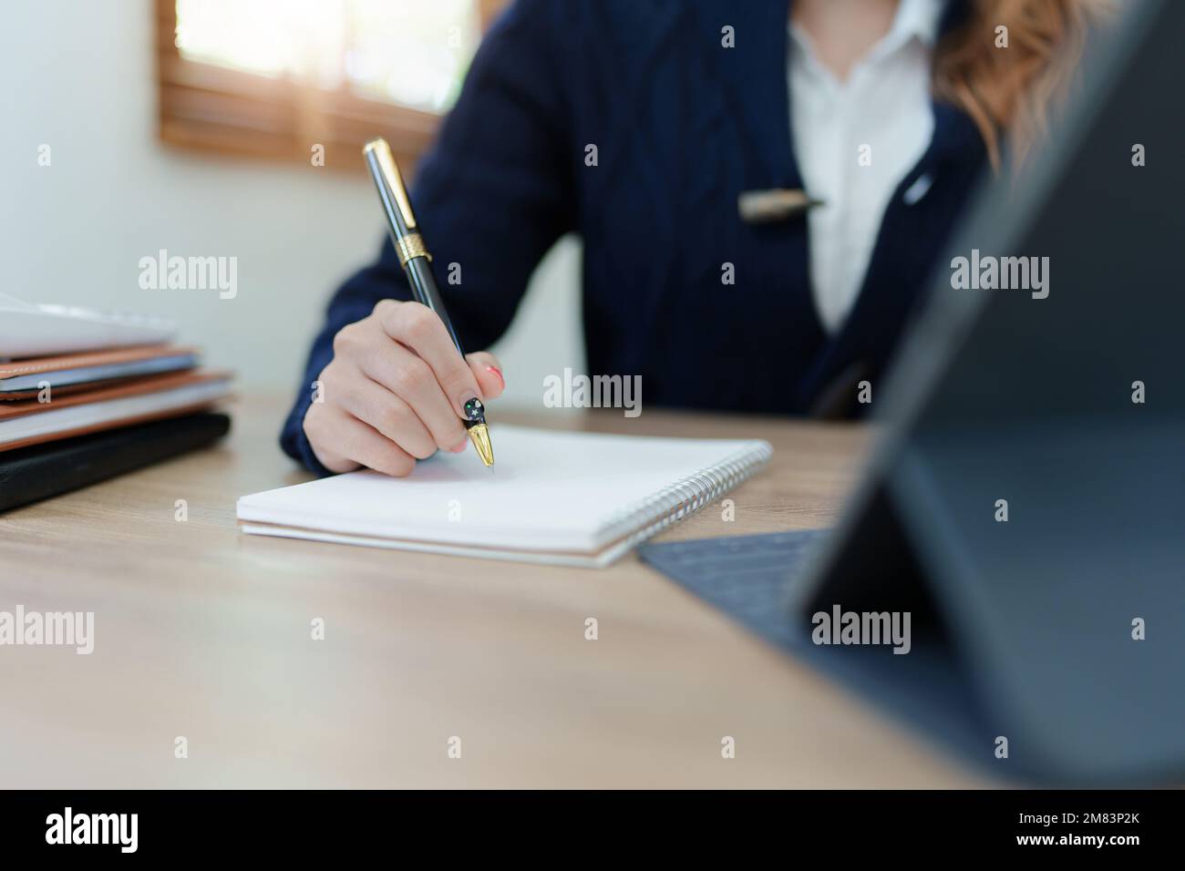 Portrait of a young Asian man showing a smiling face as she uses his notebook, tablet computer and financial documents on her desk in the early Stock Photo