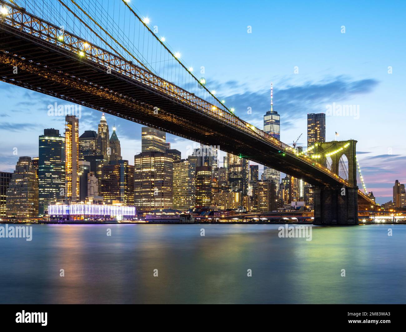 The illuminated Brooklyn Bridge with New York City skyline in he ...