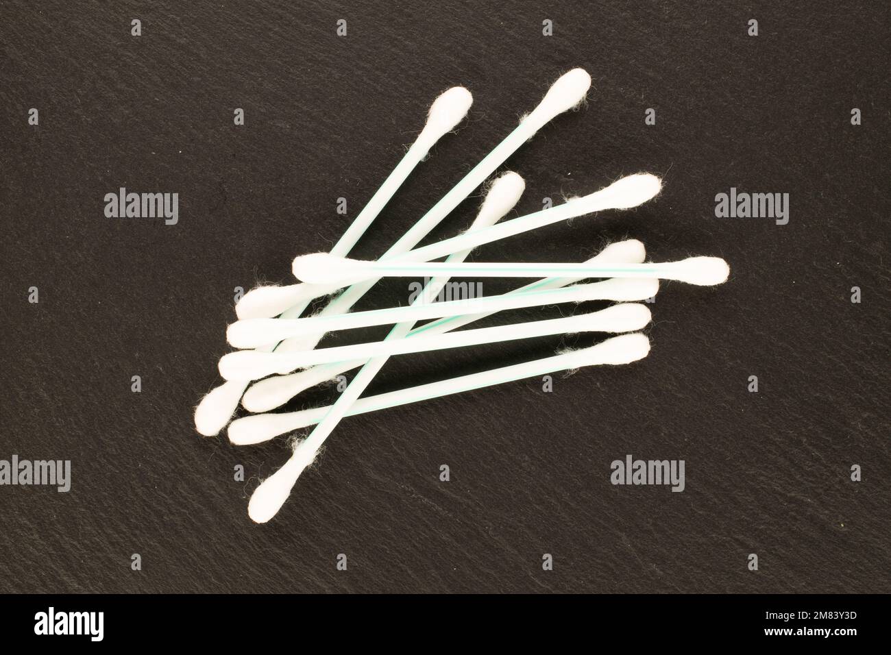 Several plastic ear sticks on slate stone, macro, top view. Stock Photo