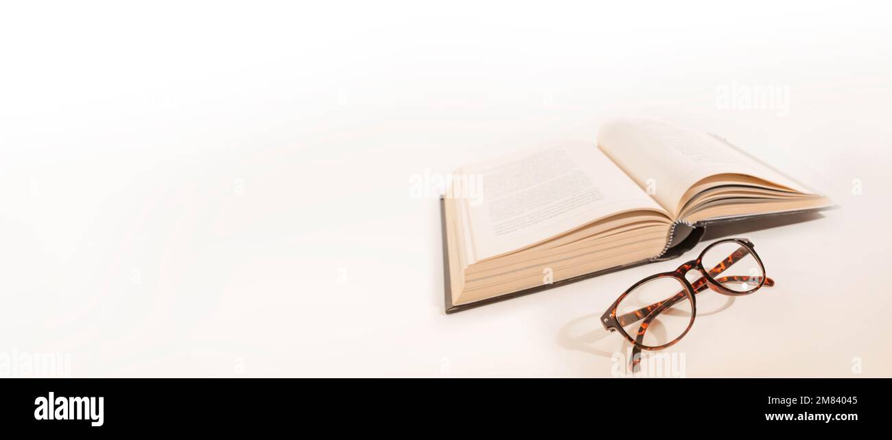 Long-sighted glasses and a big book. laying on a white background. Elderly eye health problems. Stock Photo