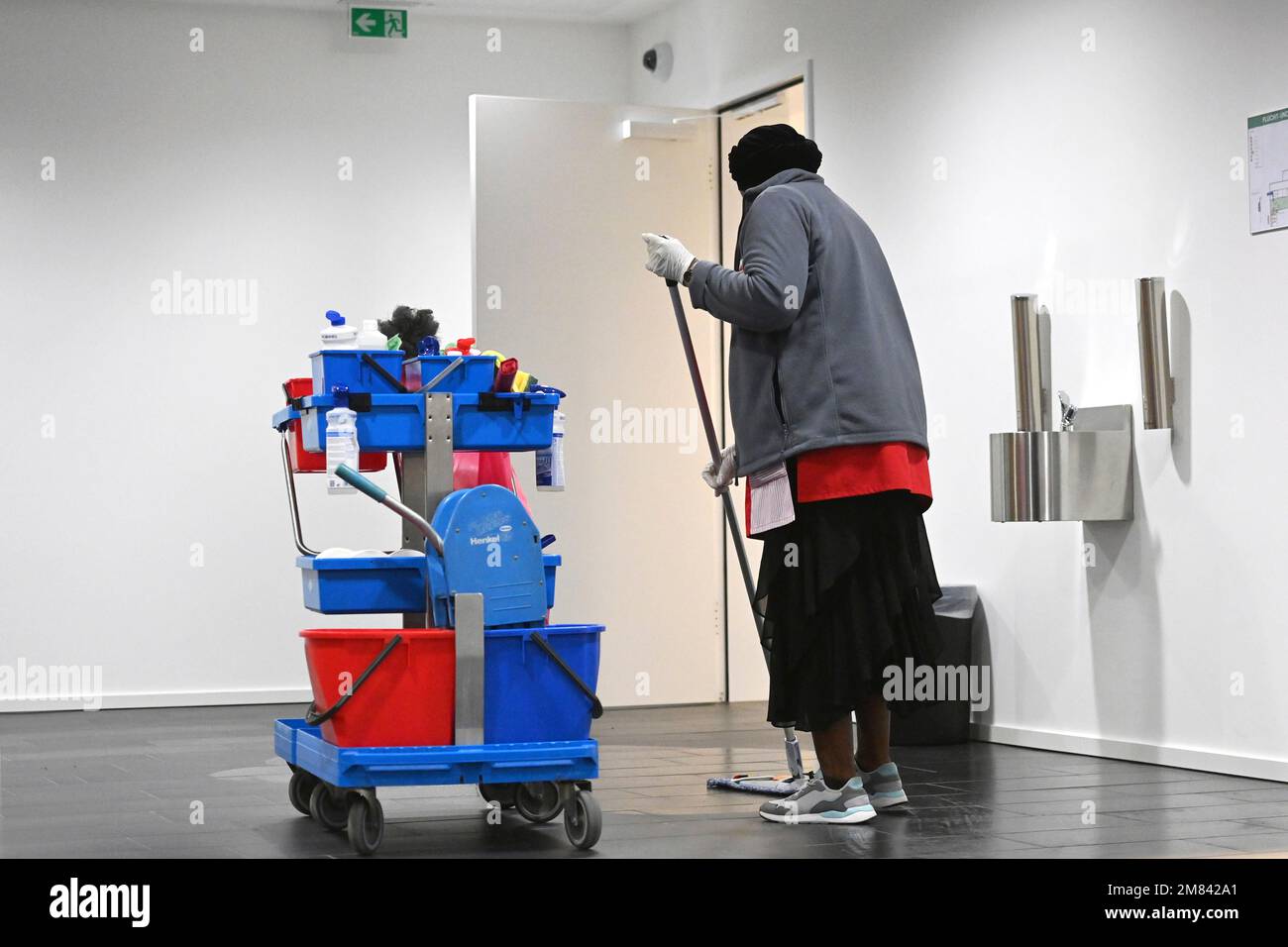 Munich, Deutschland. 11th Jan, 2023. Cleaner at work with cleaning trolley, darkskinned
