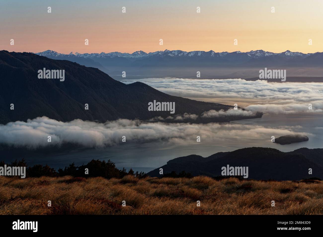 Clouds settle low over Lake Te Anau at sunrise, viewed from near Luxmore Hut on the Kepler Track Stock Photo
