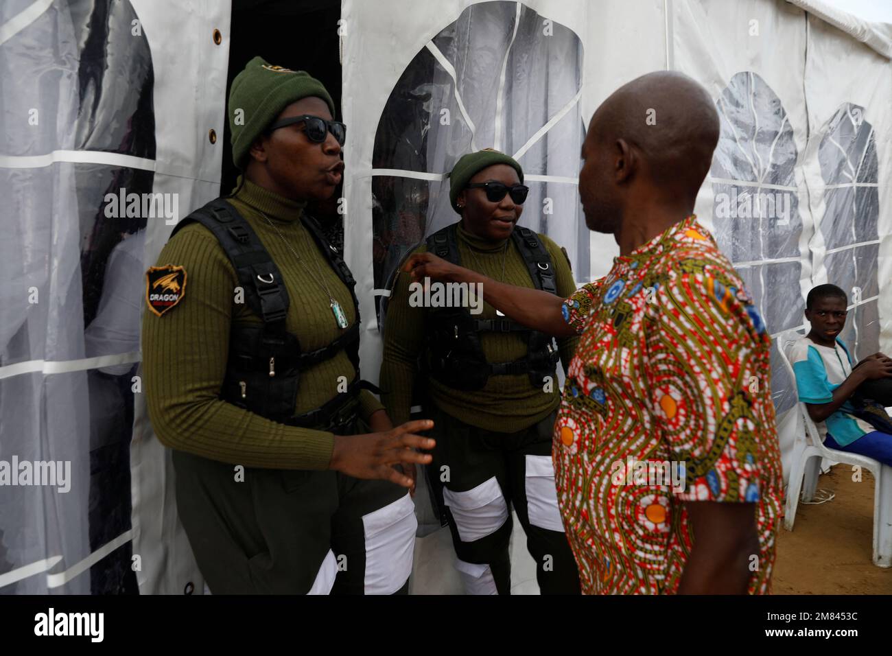 Mfoniso Peter, 29, and Glory Anthony, 34, members of the female-only security team Dragon Squad Limited, speak to a man at the entrance of a funeral, at an event centre in Eket, Akwa Ibom, Nigeria, November 19, 2022. Founded in 2018, Emem Thomas, 37, only employs women of a certain weight and shape, creating a safe space for plus-size women to excel in a field that is traditionally male-dominated. 'My team is all about plus-size ladies,' she explained. 'If you have the plus-size body then that is cool for me, before I now talk about your passion and other qualifications', she said.        REUT Stock Photo