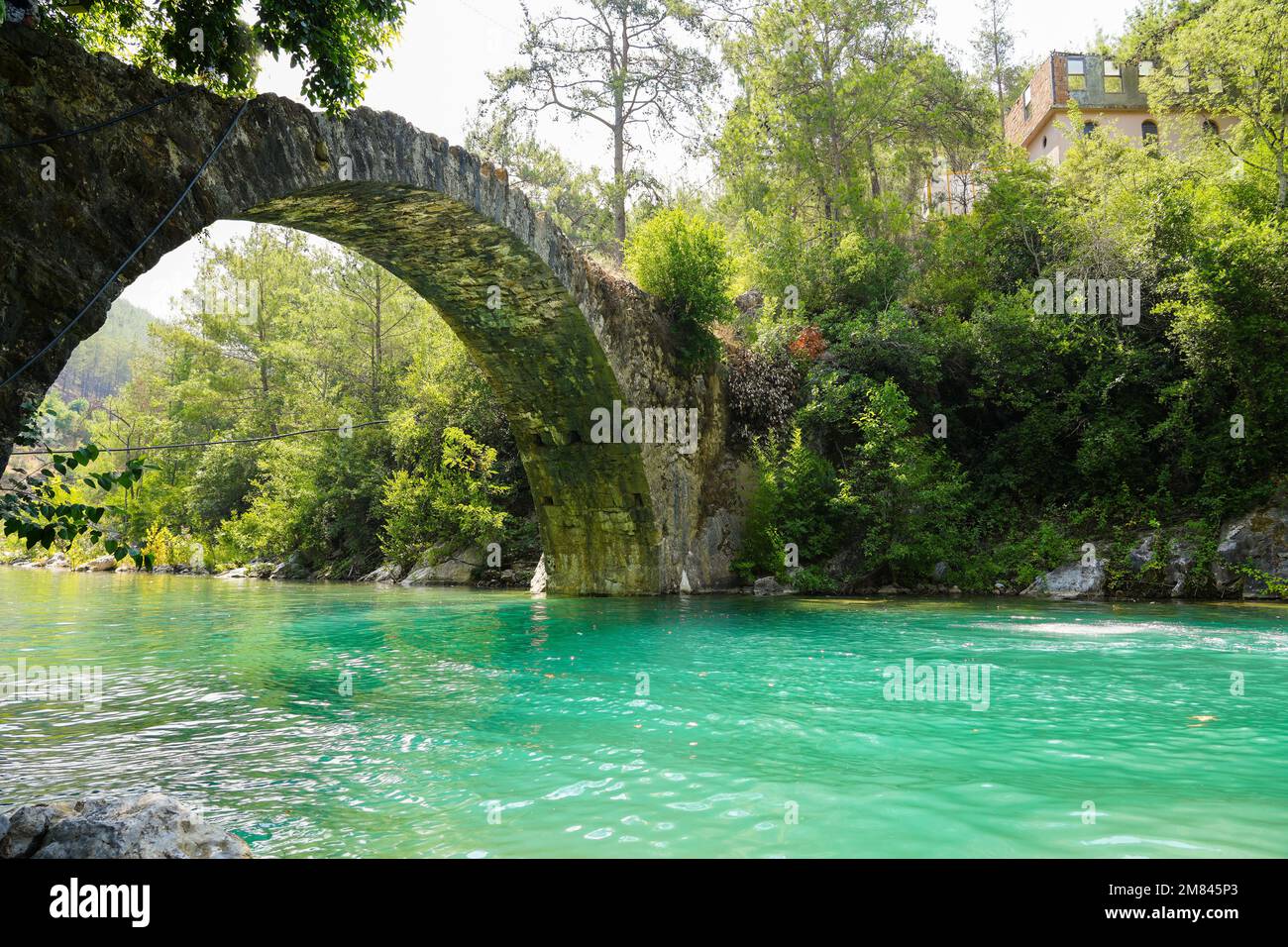 Ancient roman bridge on Dim river in Turkey. Clear turquoise water and green nature. Stock Photo