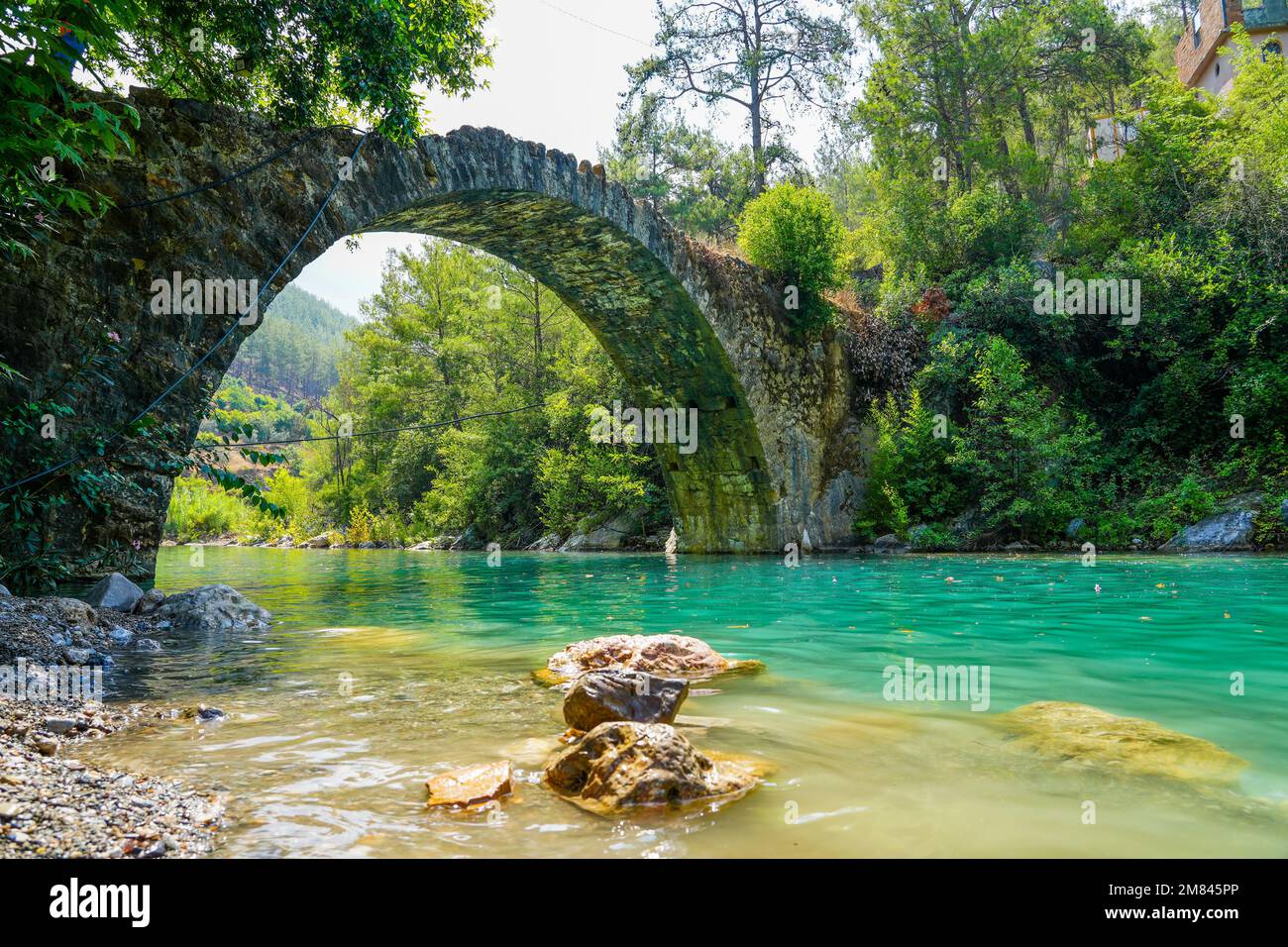 Ancient roman bridge on Dim river in Turkey. Clear turquoise water and green nature. Stock Photo