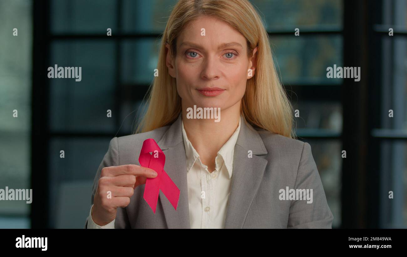 Headshot portrait Caucasian middle-aged woman hold red ribbon in office businesswoman with HIV AIDS awareness disease prevention protection sign Stock Photo