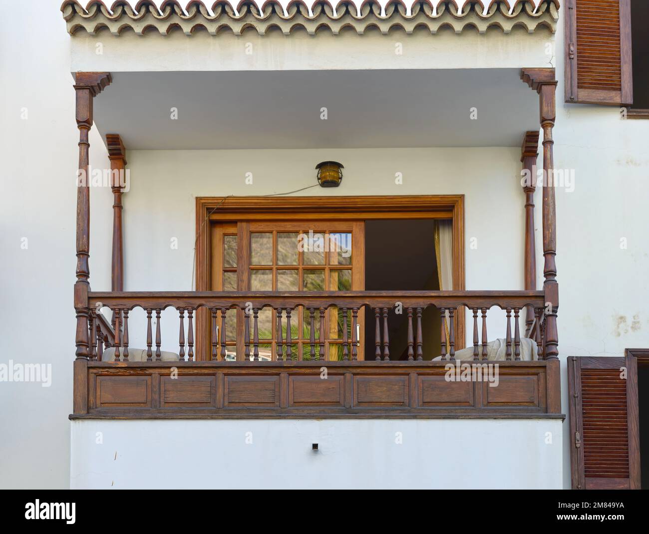 Closeup of balcony with wooden canopy, railing and horizontal sun blind