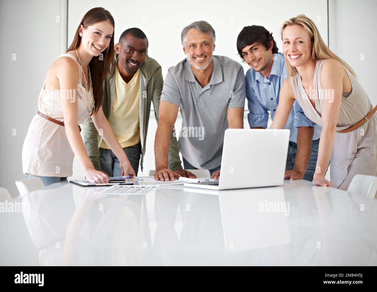 Dynamic business pros. Five colleagues using a laptop in the boardroom. Stock Photo