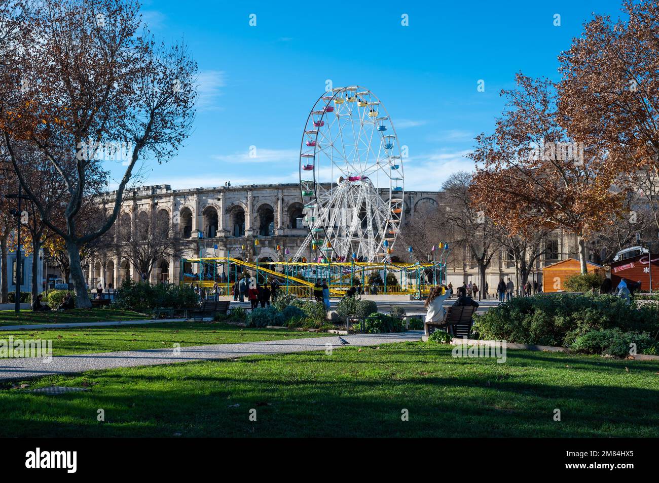 Park, ferris wheel and arena ampitheater of Nimes, france, December 2022 Stock Photo