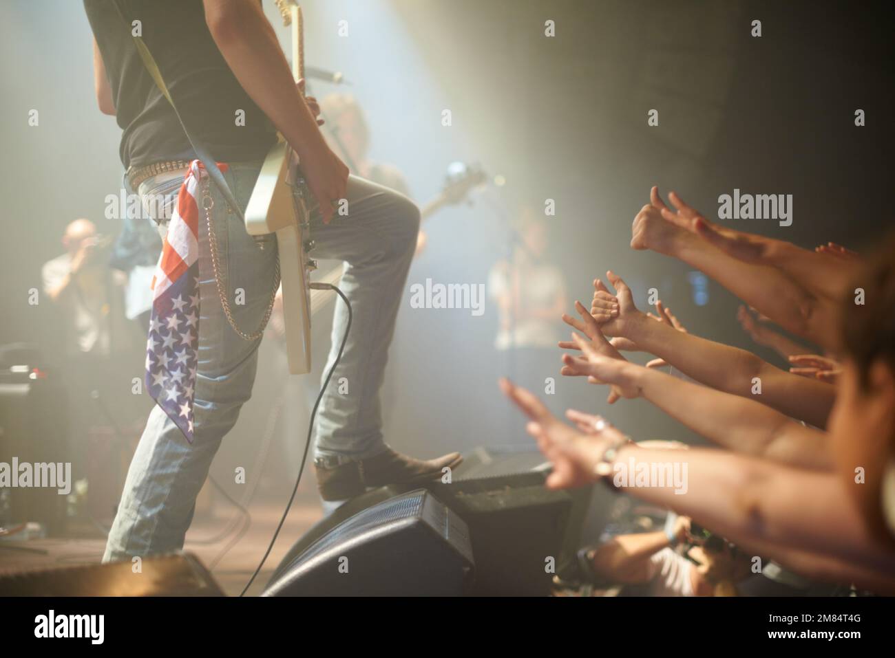 They cant get enough. a crowd of music fans reaching up at a guitarist on stage. Stock Photo