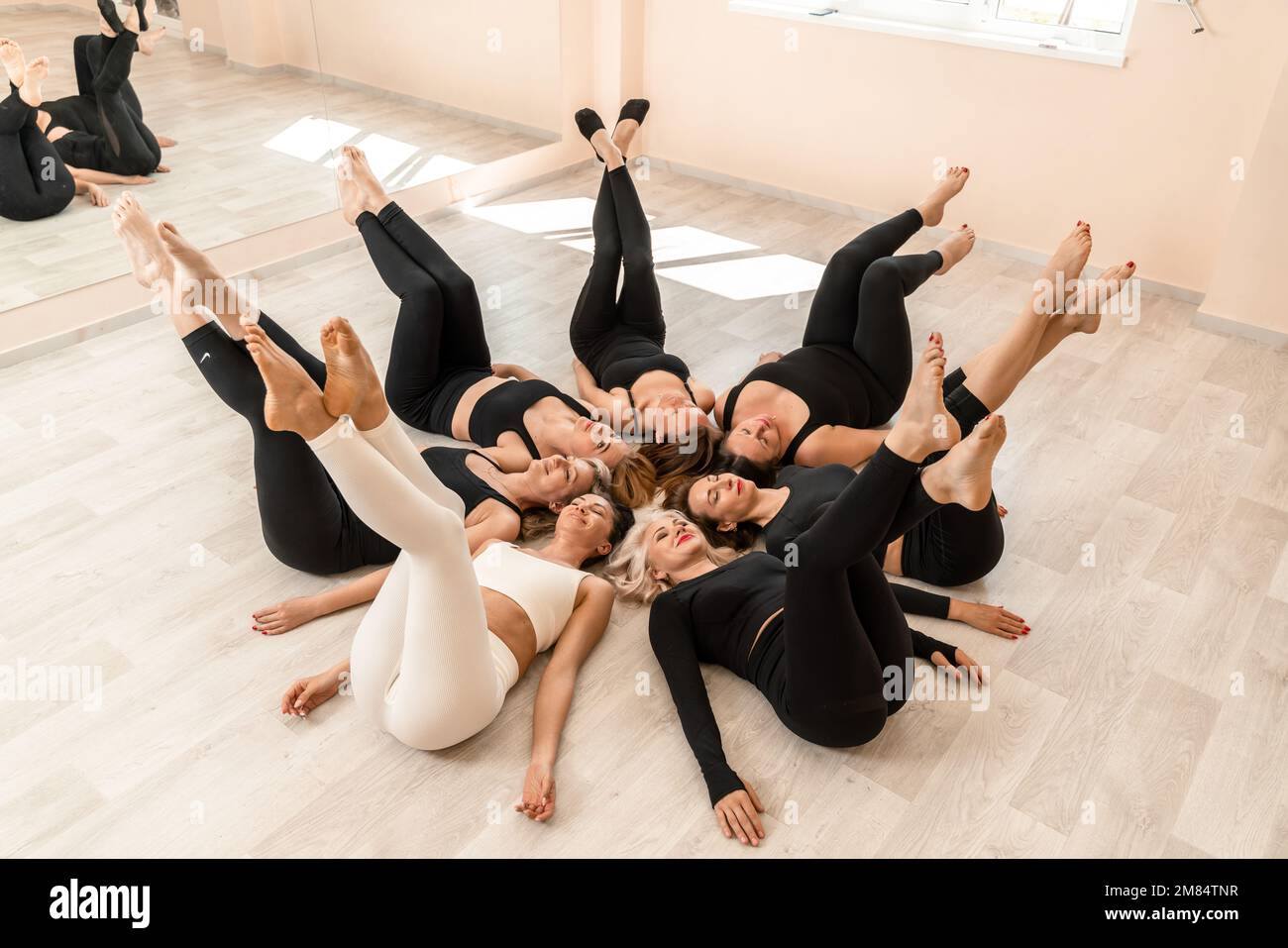 Seven happy women lie on their backs on the floor with their heads ...