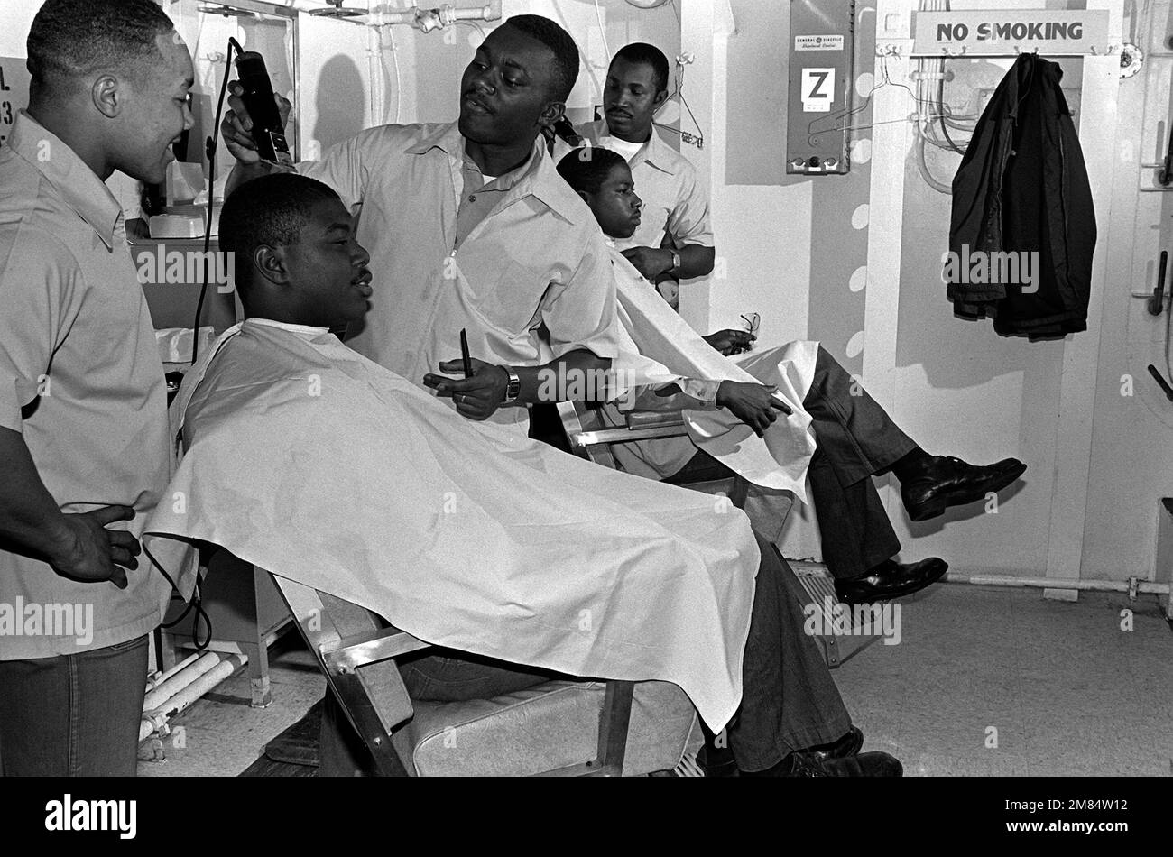 Navy barbers give two crew members a trim in the enlisted on