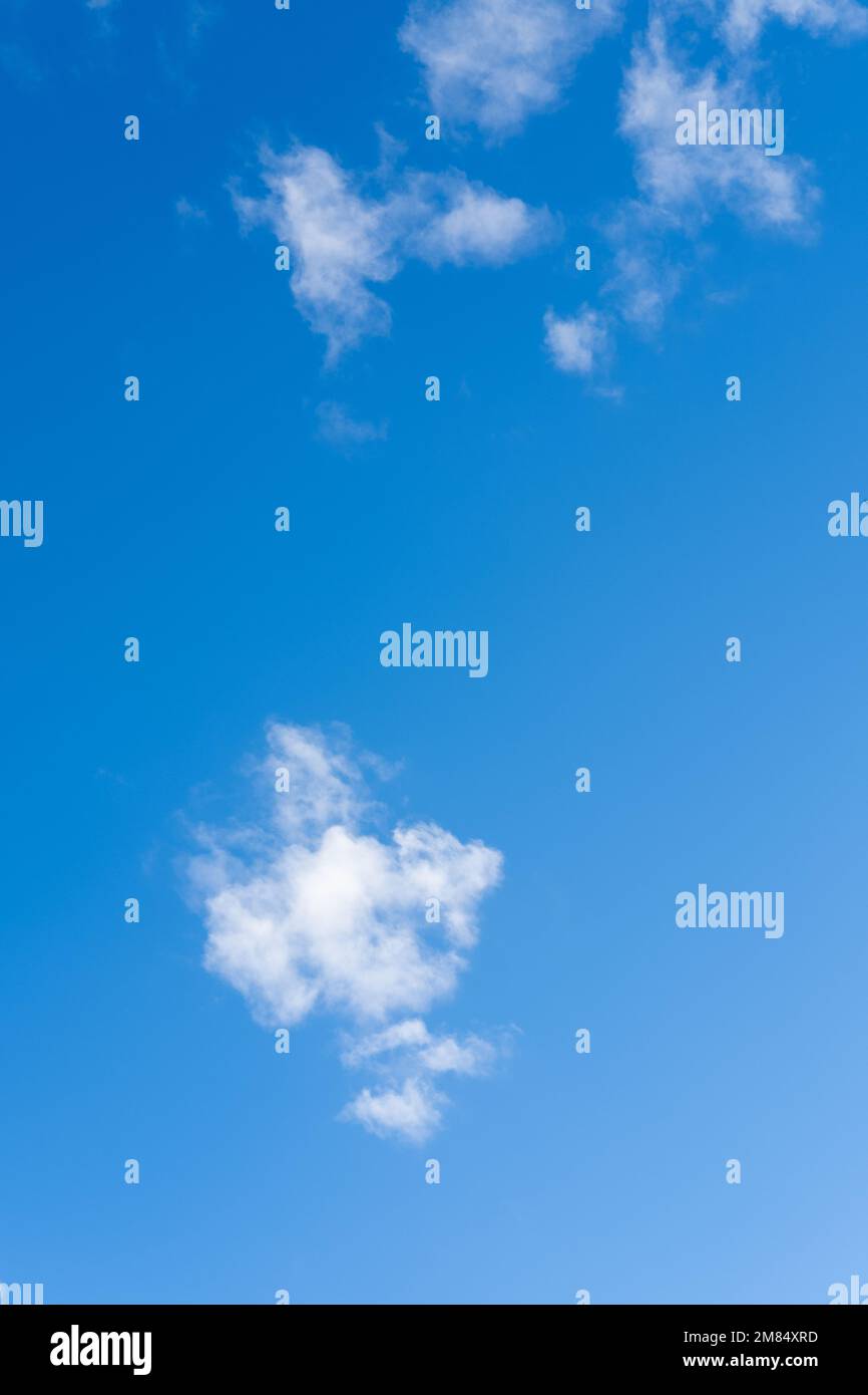 Blue sky with fluffy thin white clouds, vertical frame. Cloud