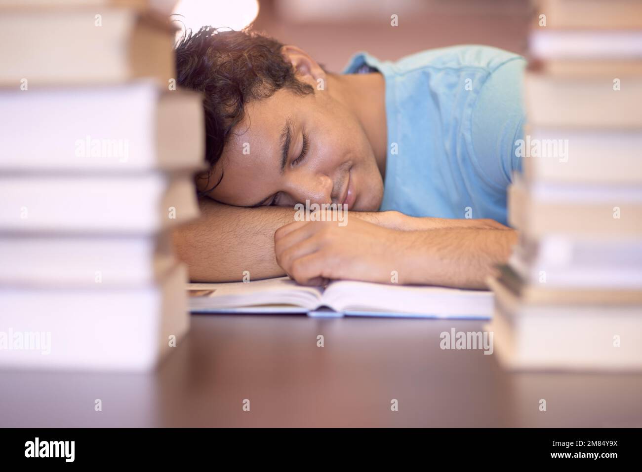 Exam exhaustion. A young student sleeping on his desk after a tiring study session. Stock Photo