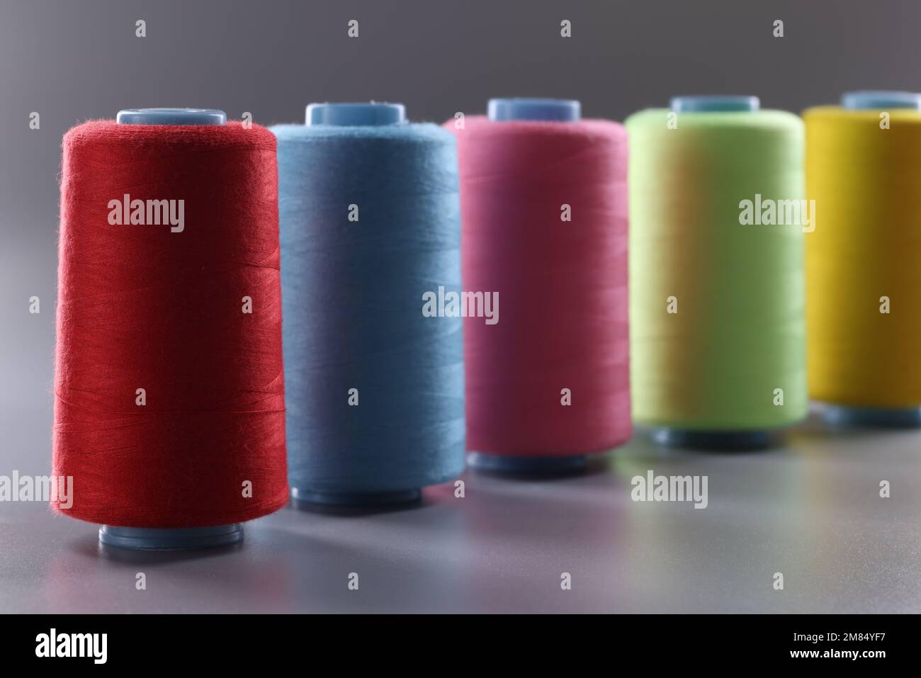 Multicolored thread spools on gray background. Set of colored threads Stock Photo