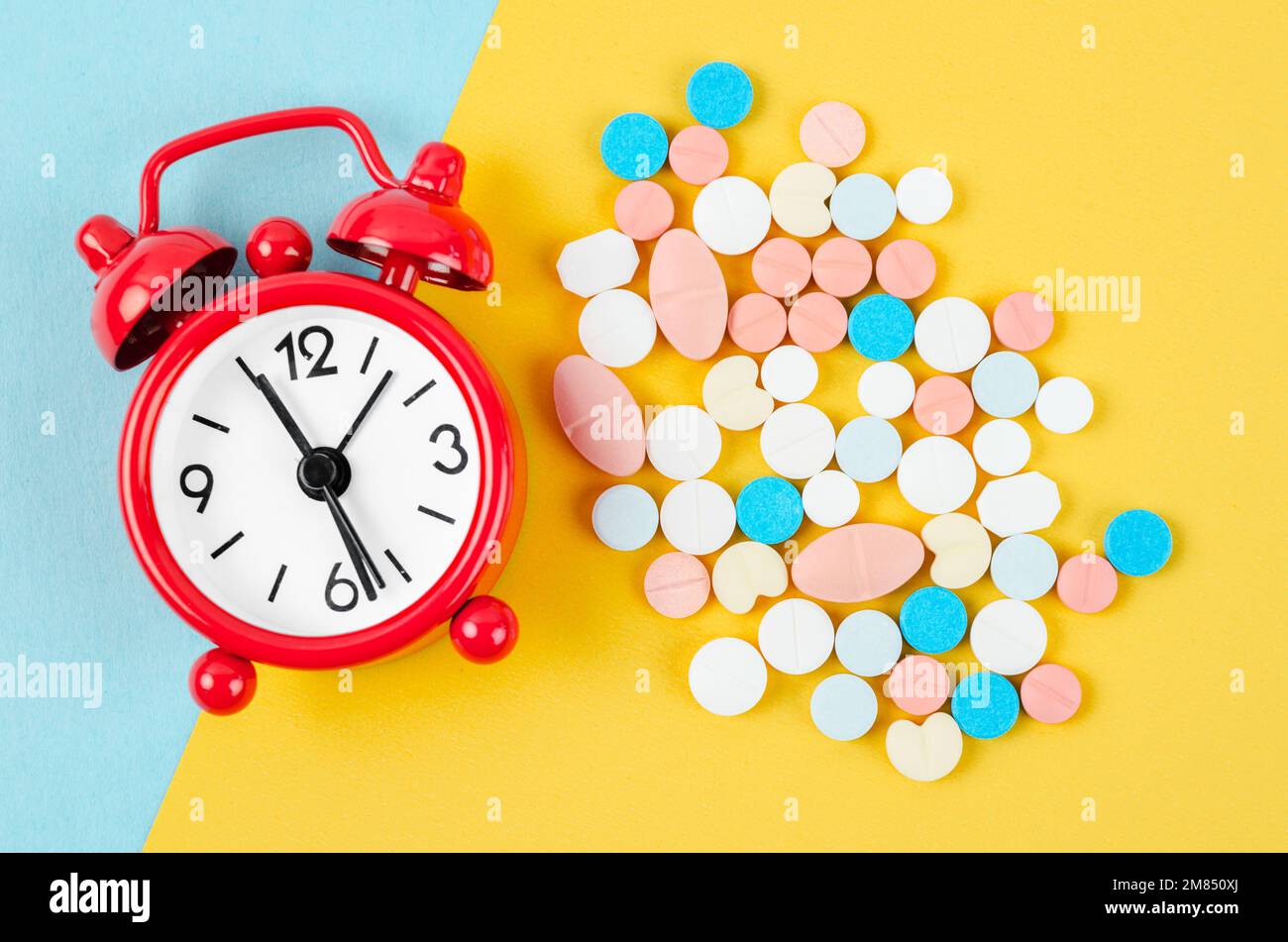 Alarm clock and many drug on a yellow background. Taking medicine at