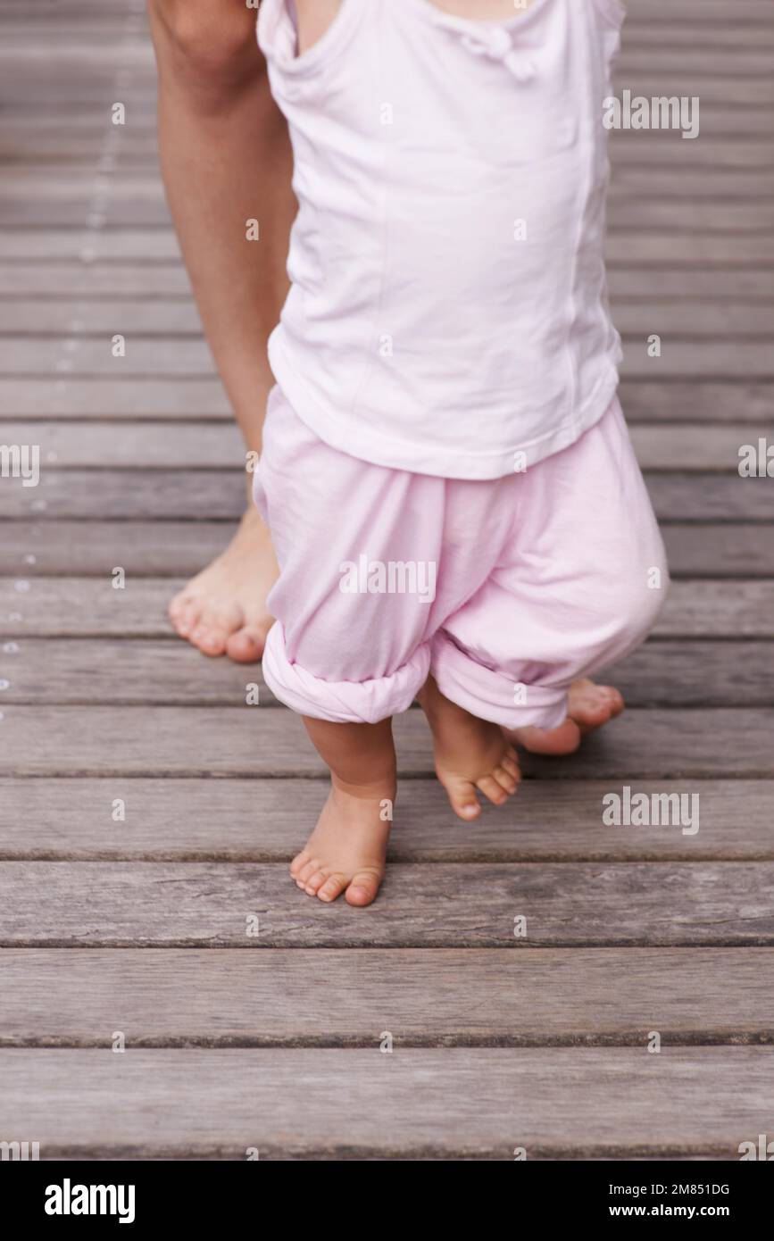 Momentous milestones. Cropped closeup image of a mother helping her baby to take her first steps. Stock Photo