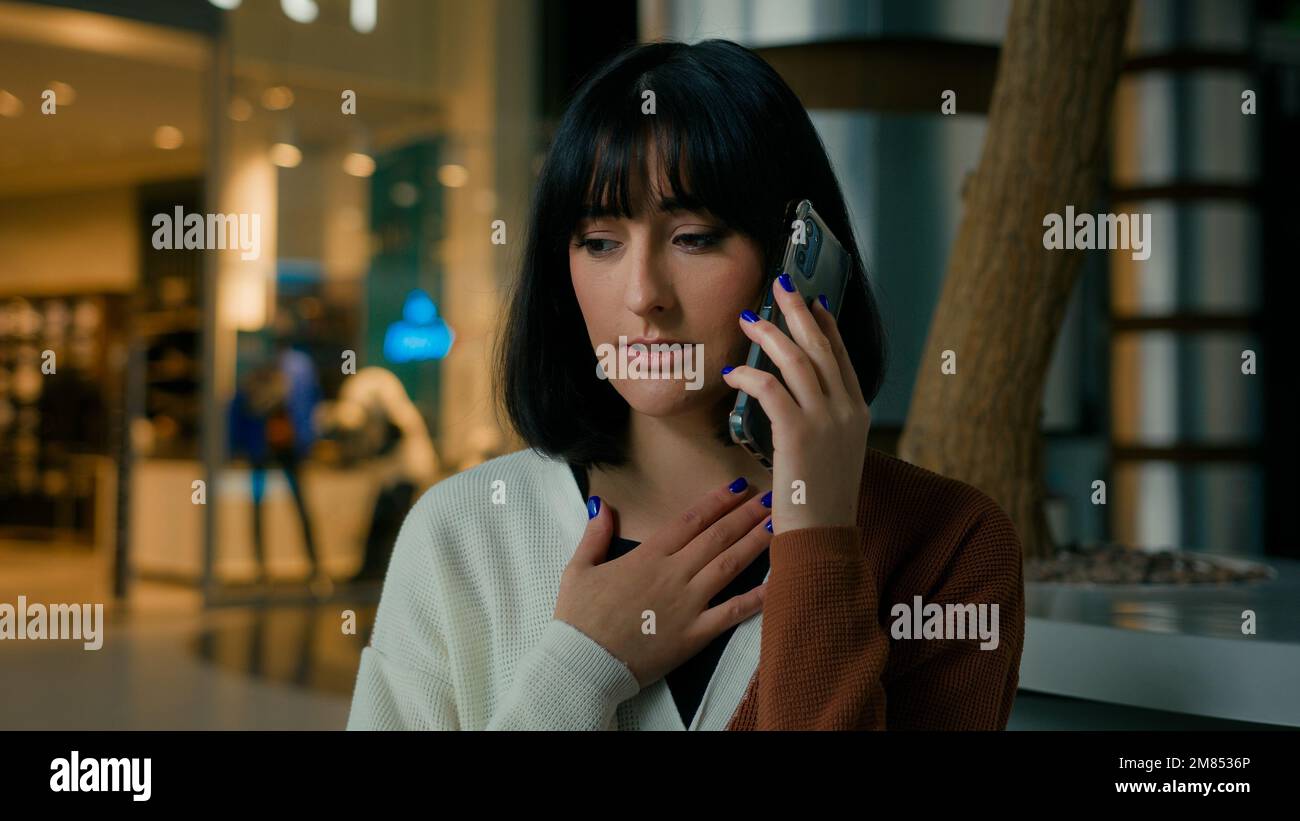 Worried upset woman indoors answer call talking phone disappointed shocked with smartphone conversation business problem lady speaking worry Stock Photo
