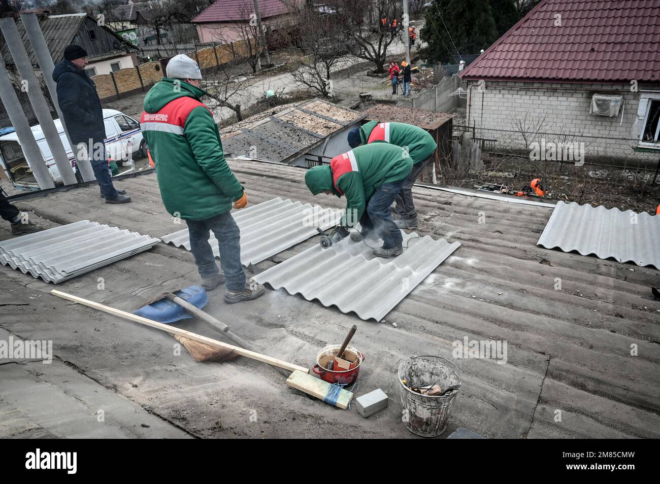 ZAPORIZHZHIA, UKRAINE JANUARY 12, 2023 Utility workers cut corrugated fibre cement roofing