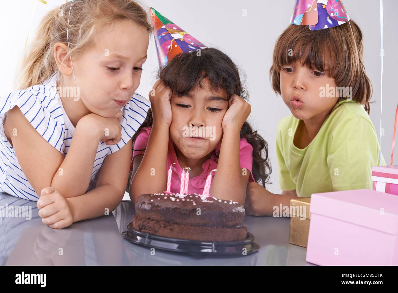 Make a birthday wish. a young girl blowing out her birthday candles as