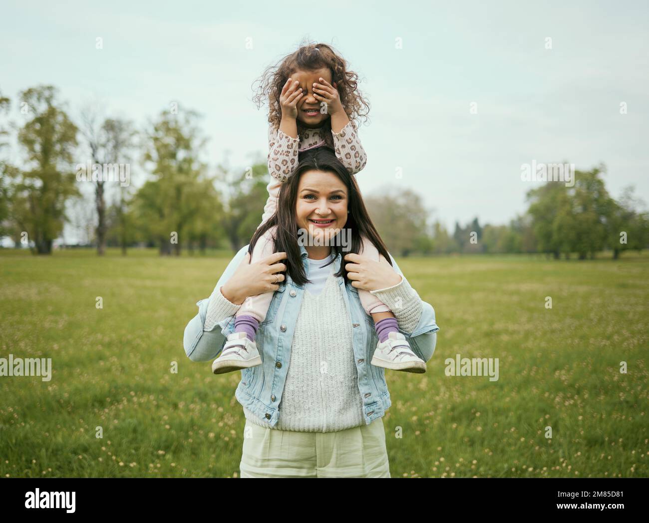 Mom, girl and sitting on shoulders outdoor for happiness, bonding or care in nature together in spring. Woman, kid and happy family for vacation, love Stock Photo