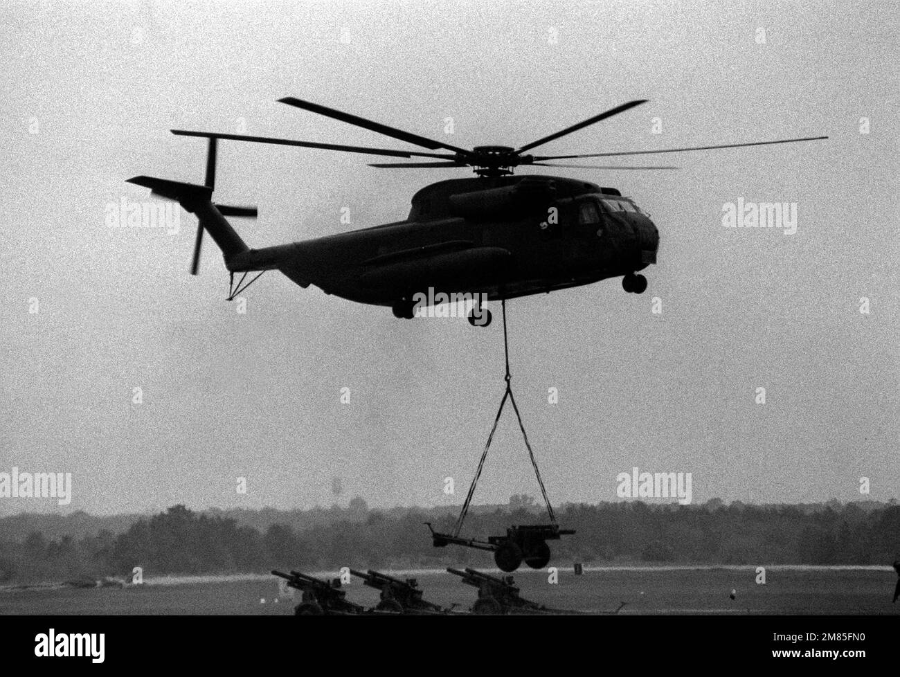 A CH-53 Sea Stallion helicopter lift a howitzer off the ground during ...