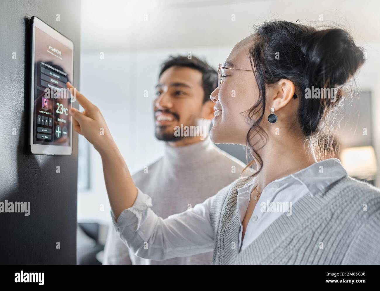 Smart home technology, wall system and couple with digital dashboard for air conditioning, safety security network or house automation. App software Stock Photo