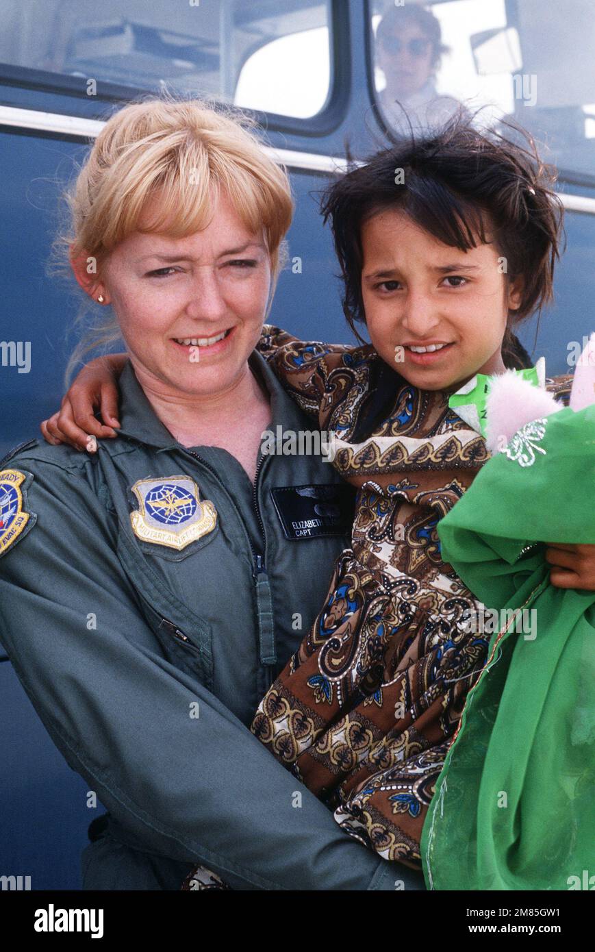 A member of the Military Airlift Command's 2nd Aeromedical Evacuation Squadron holds an Afghan child following the girl's arrival on base aboard a C-141B Starlifter aircraft. The child is one of 25 Afghan civilians being transported to the US Air Force Regional Medical Center at Weisbaden, West Germany, for specialized medical treatment following injuries incurred as a result of Afghanistan's civil war. The patients will later be evacuated to hospitals in Europe and the United States for donated medical assistance. Base: Rhein-Main Air Base Country: Deutschland / Germany (DEU) Stock Photo