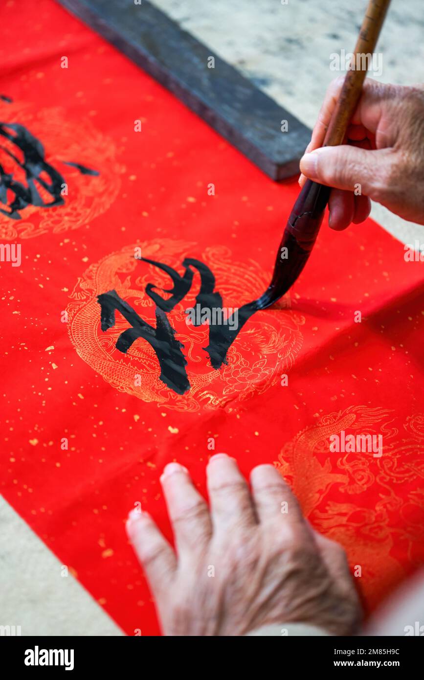 An old Chinese calligrapher is writing Chinese Spring Festival couplets ...