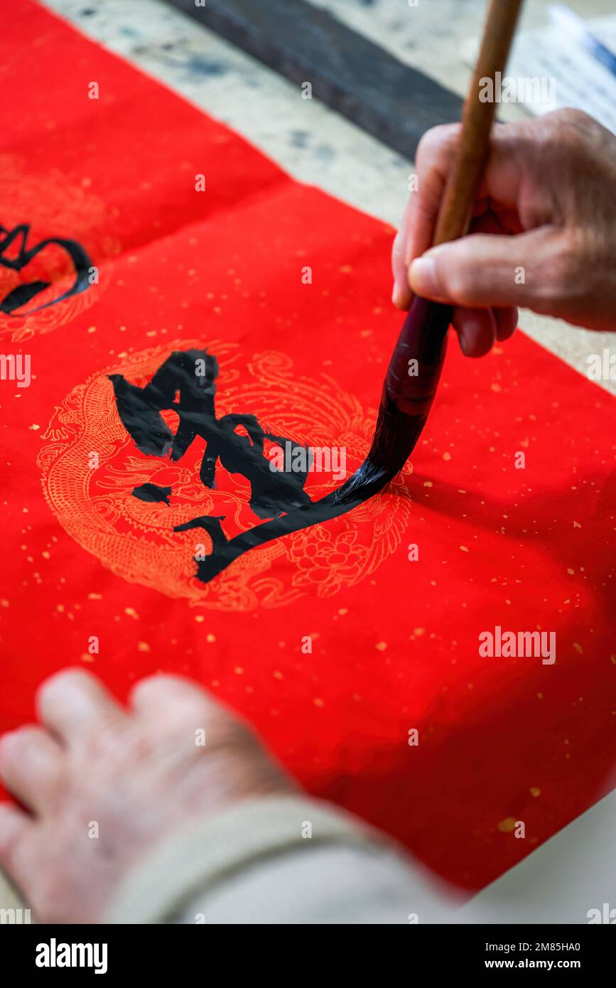 An old Chinese calligrapher is writing Chinese Spring Festival couplets ...