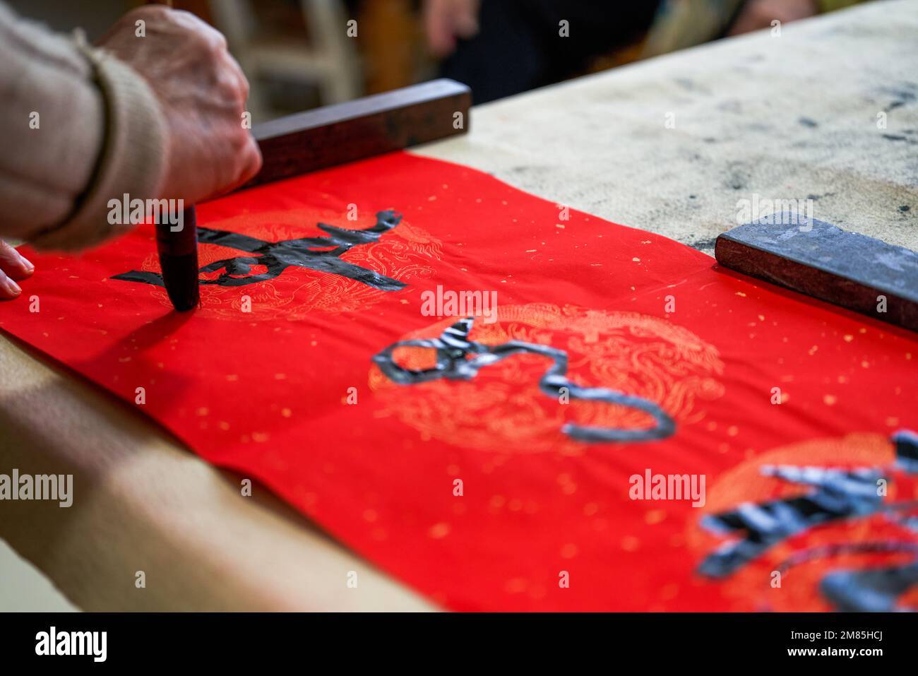 An old Chinese calligrapher is writing Chinese Spring Festival couplets ...
