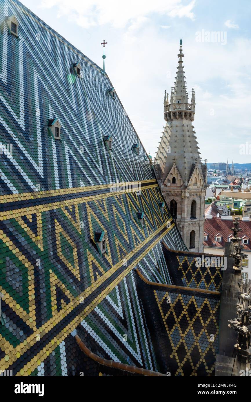From the top of St Stephens Cathedral in Vienna, a beautiful tiled roof, views of the city and some workmen doing maintenance work high above the city Stock Photo