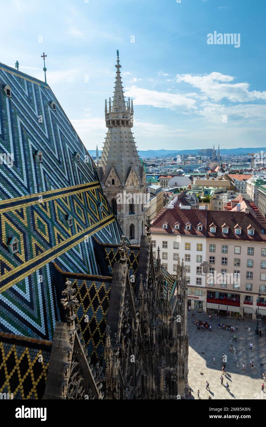 From the top of St Stephens Cathedral in Vienna, a beautiful tiled roof, views of the city and some workmen doing maintenance work high above the city Stock Photo