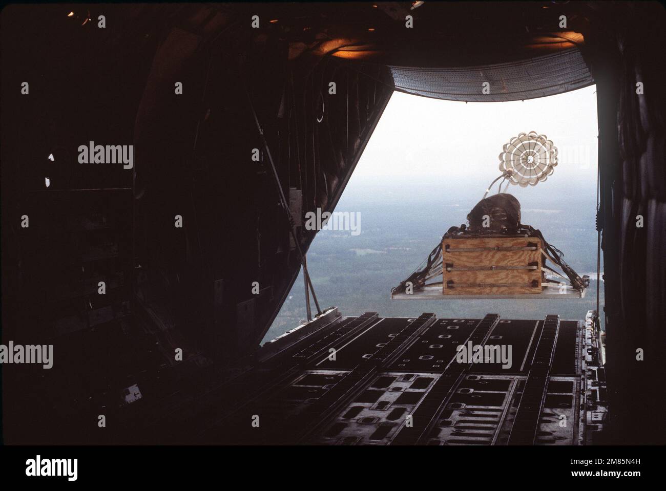 A pallet of supplies is airdropped from the back of a C-130 Hercules ...