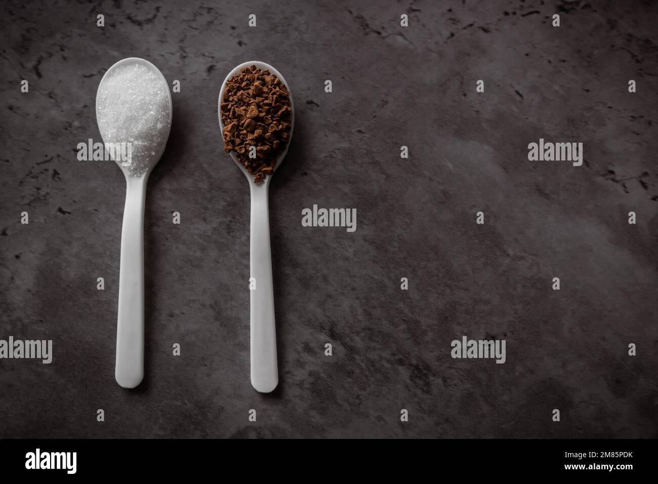 Two spoonfuls of instant coffee and sugar on the kitchen counter in equal portions. Top view flat lay with empty space for text. Excess sugar concept Stock Photo