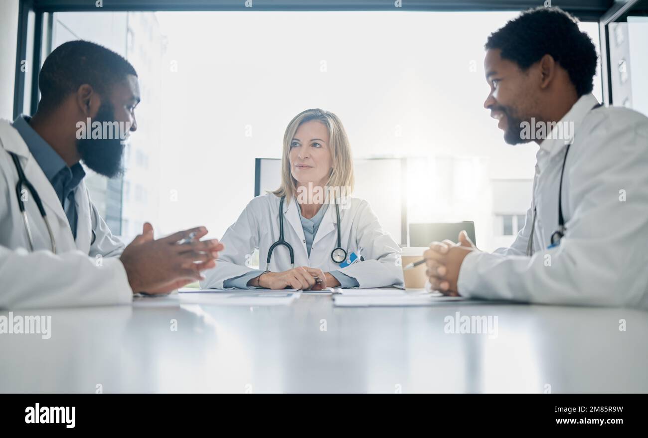 Healthcare, meeting and team of doctors talking in hospital, clinic or health care facility boardroom. Teamwork, communication and medical workers in Stock Photo