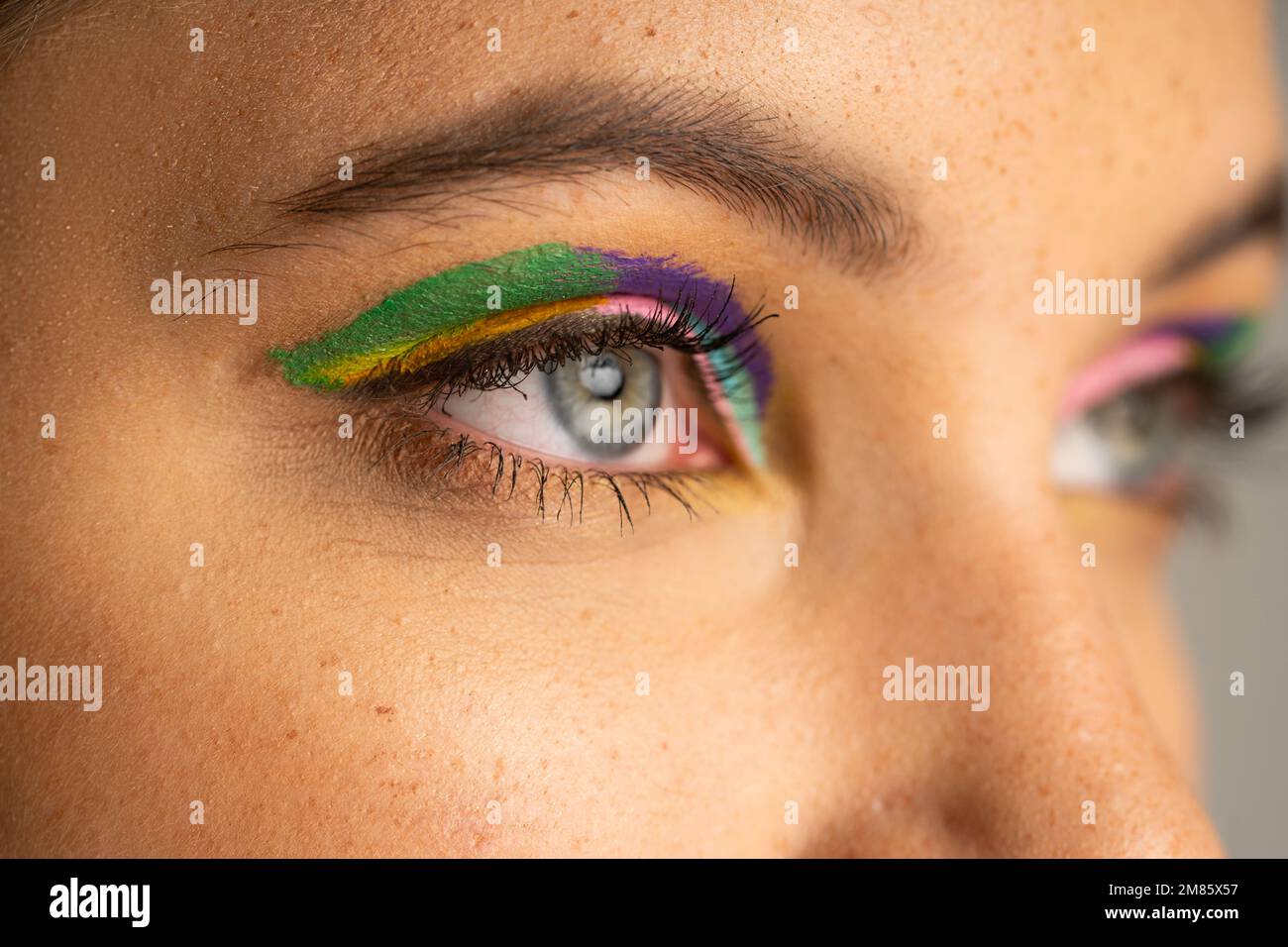 Cropped view of teen girl with freckles and colorful eyeshadows isolated on grey Stock Photo