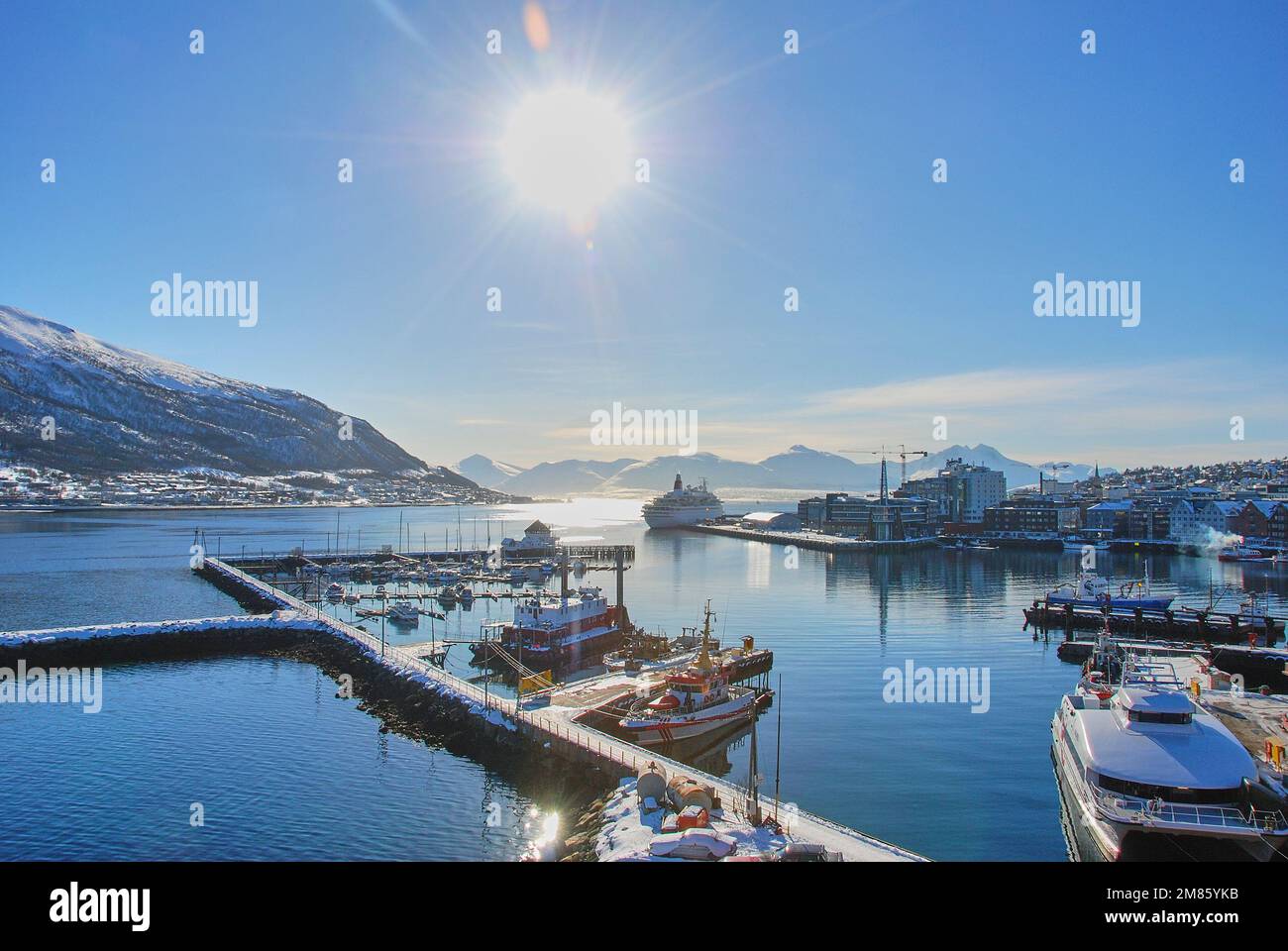 Cruise ship in the winter landscape of the port of Tromso in a fjord at the coastline of northern Norway with snow covered mountains in the background Stock Photo