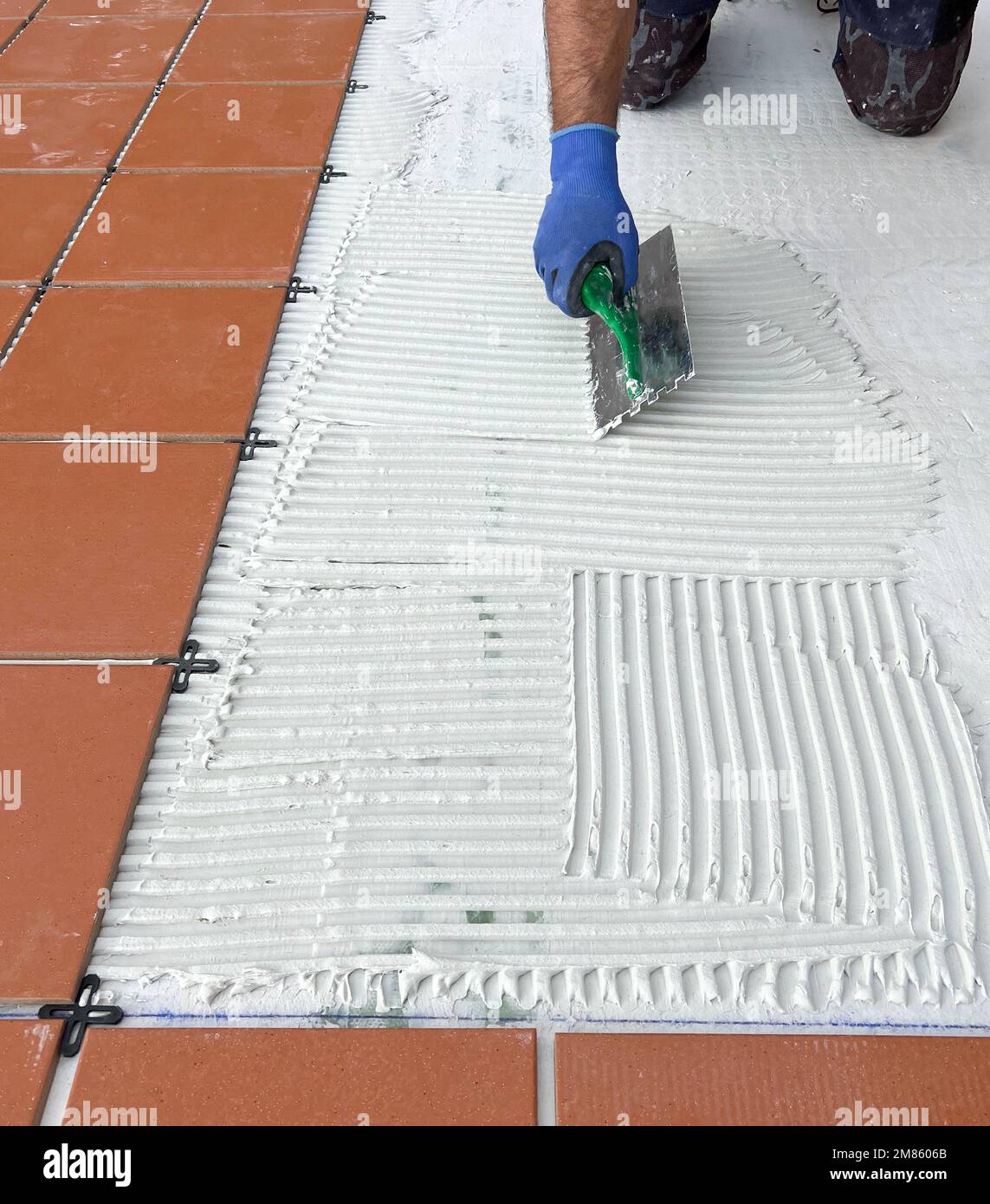 worker spreads the cement glue before applying the ceramic tiles Stock
