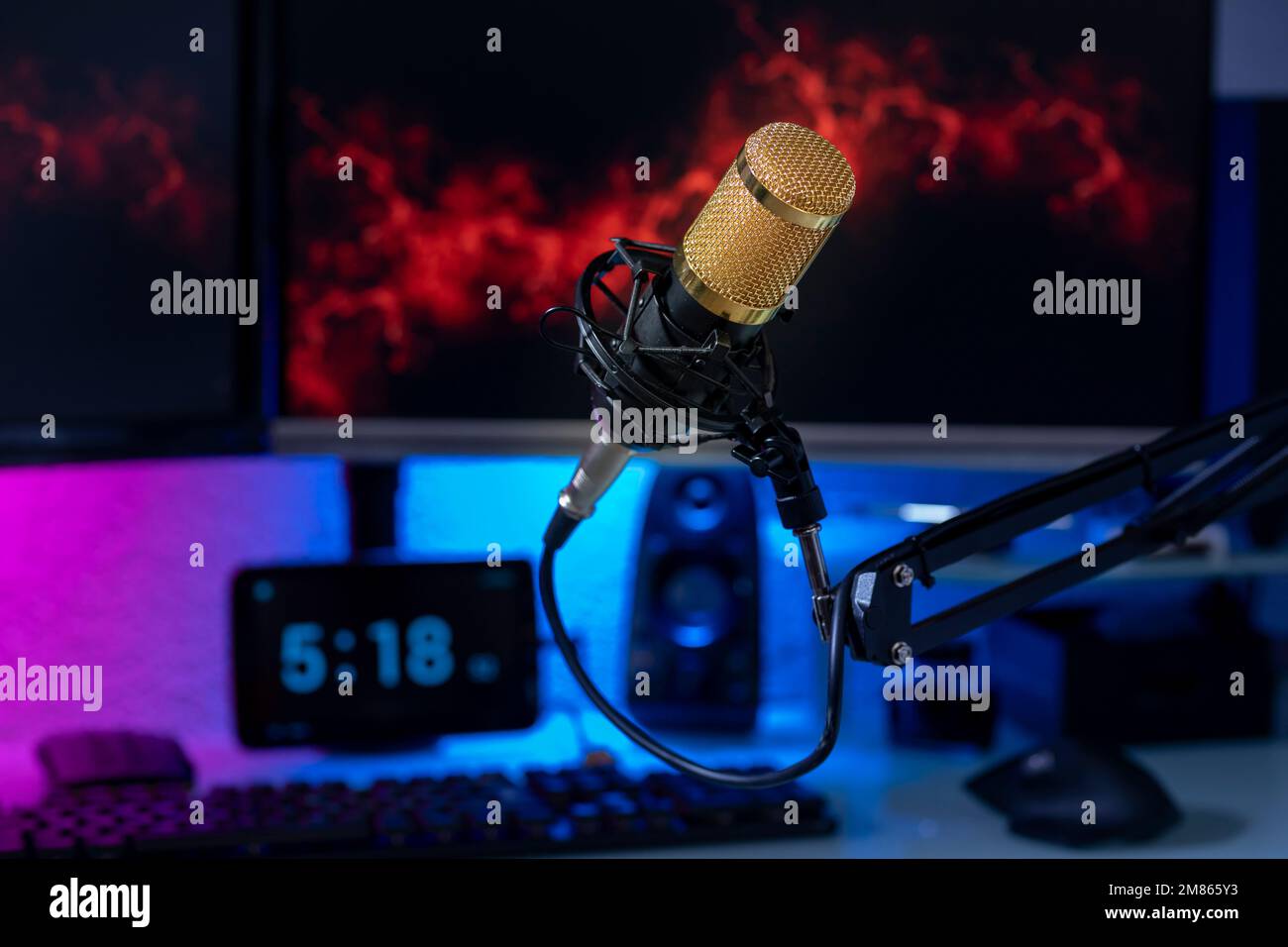 Professional microphone with gamer setup in the background and colored lights. Stock Photo
