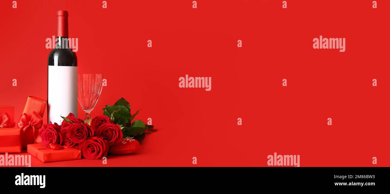 Bottle of wine, rose flowers, glass and gifts on red background with ...