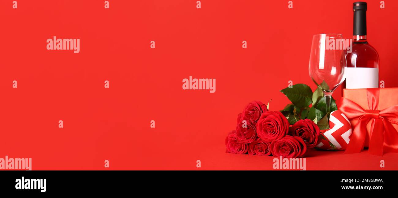 Bottle of wine, glass, rose flowers and gifts on red background with ...