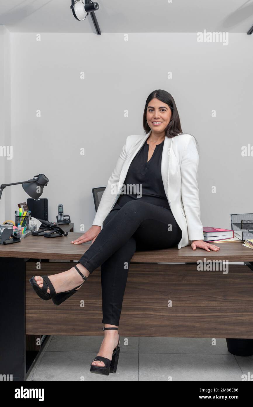 Happy, confident and successful Latin business woman sitting at her ...